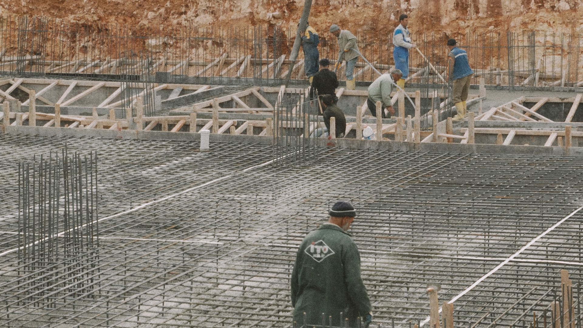 Crew placing concrete over a rebar-reinforced foundation mat